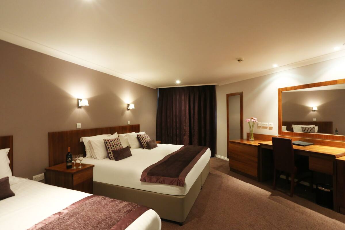 A hotel room with two beds, a desk, and a large mirror.