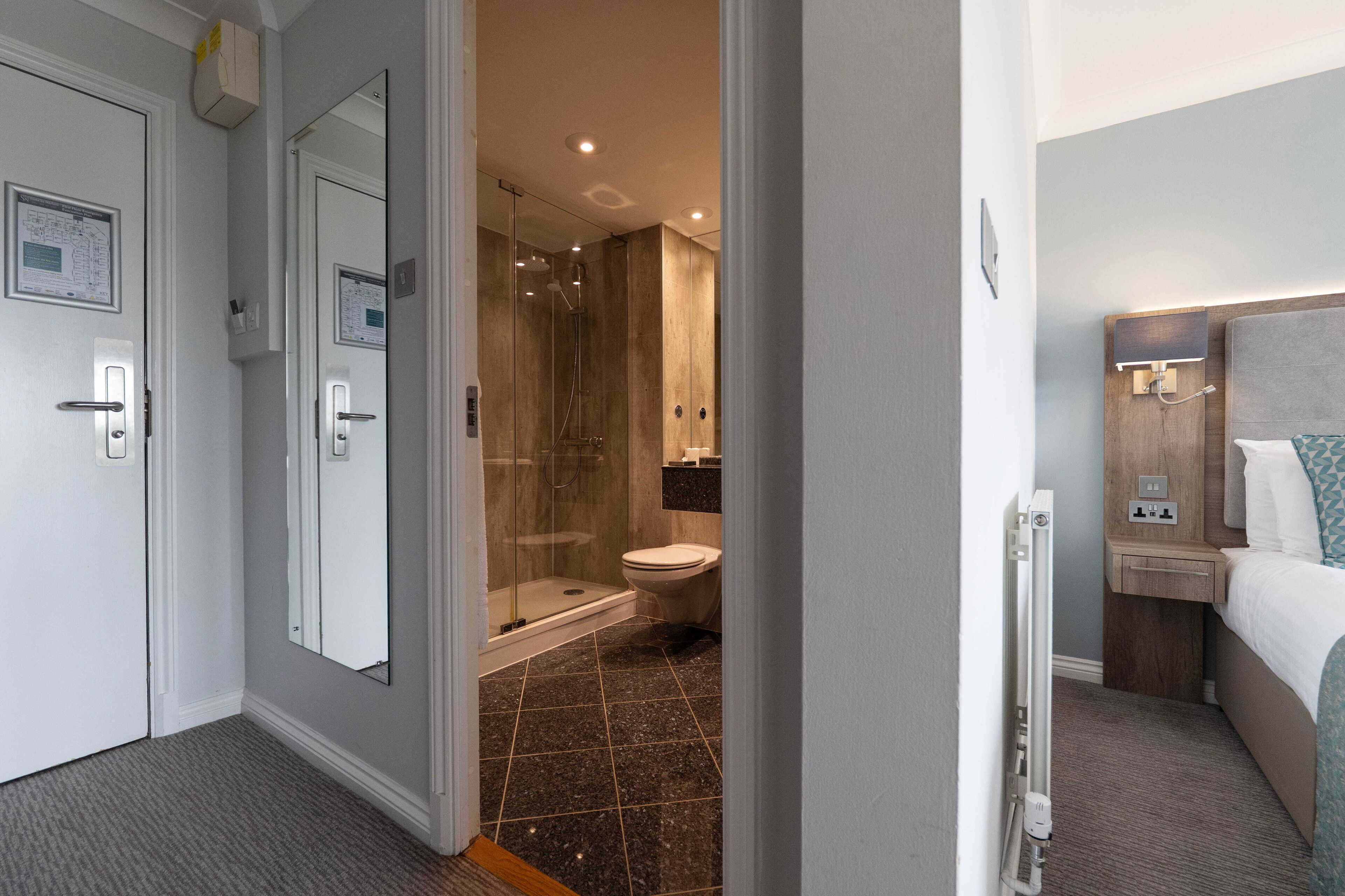 A hotel room with a shower, toilet, and a bed.