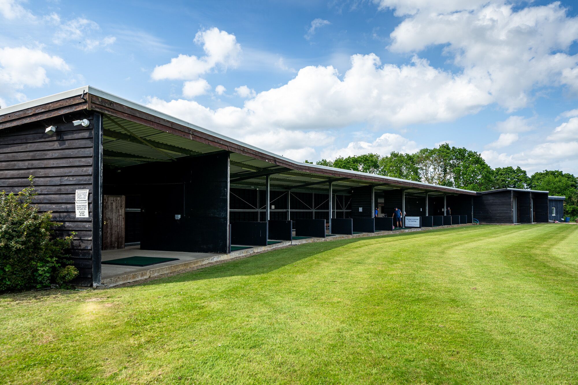 A stable with covered stalls and a grassy area in front.