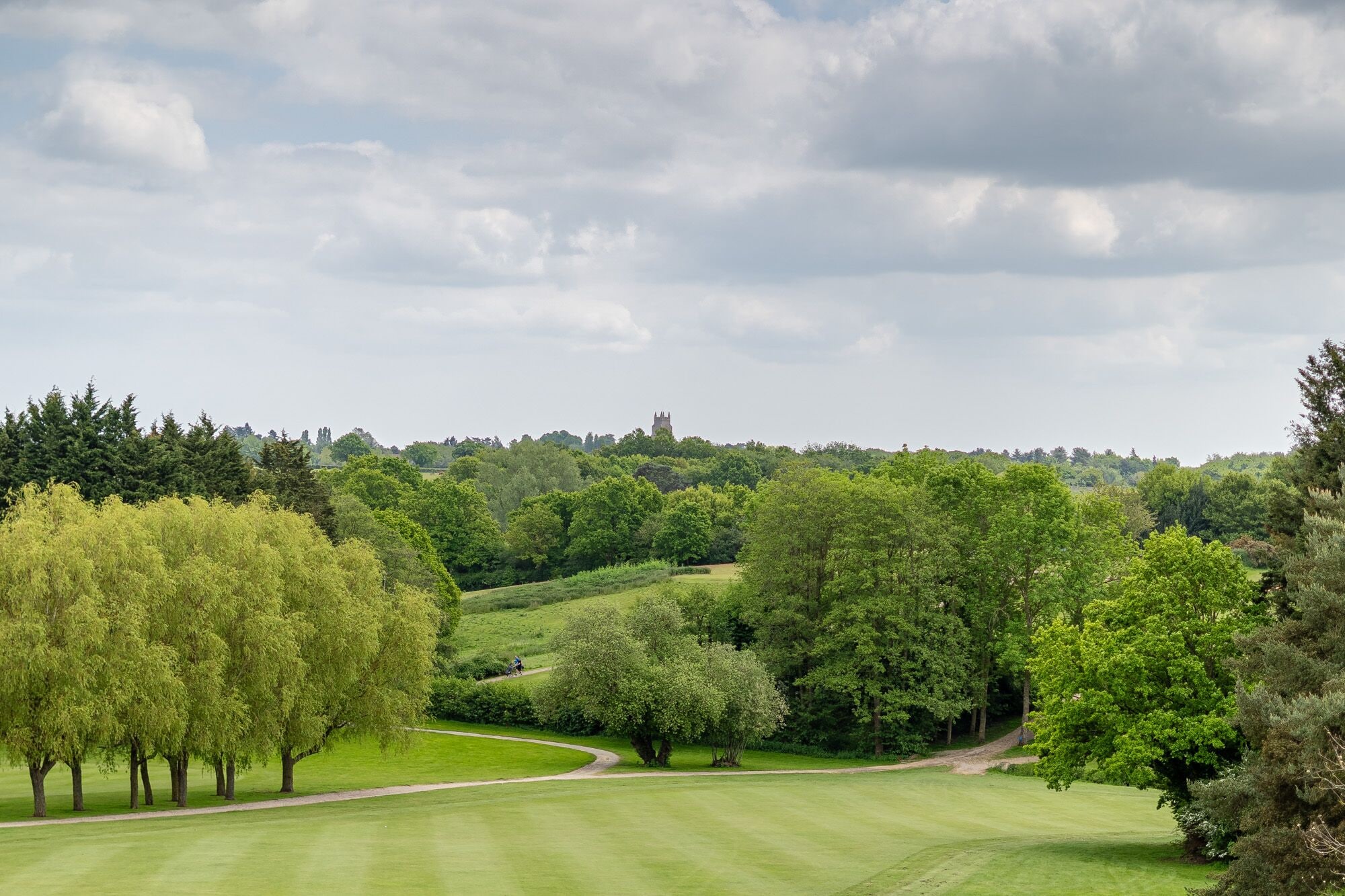 Un campo de golf con un castillo al fondo, rodeado de exuberante vegetación.