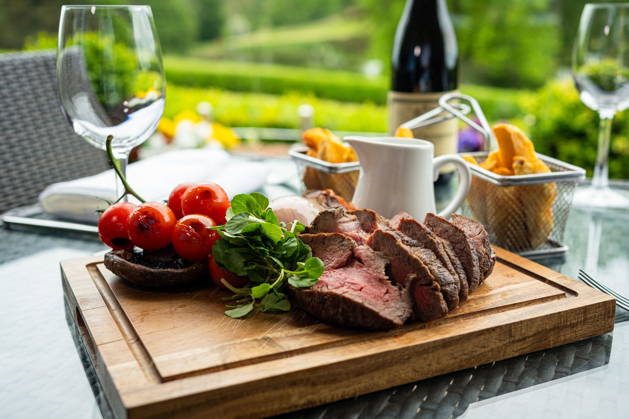 Ein Holztisch mit geschnittenem Rindfleisch, Kirschtomaten und Salat.