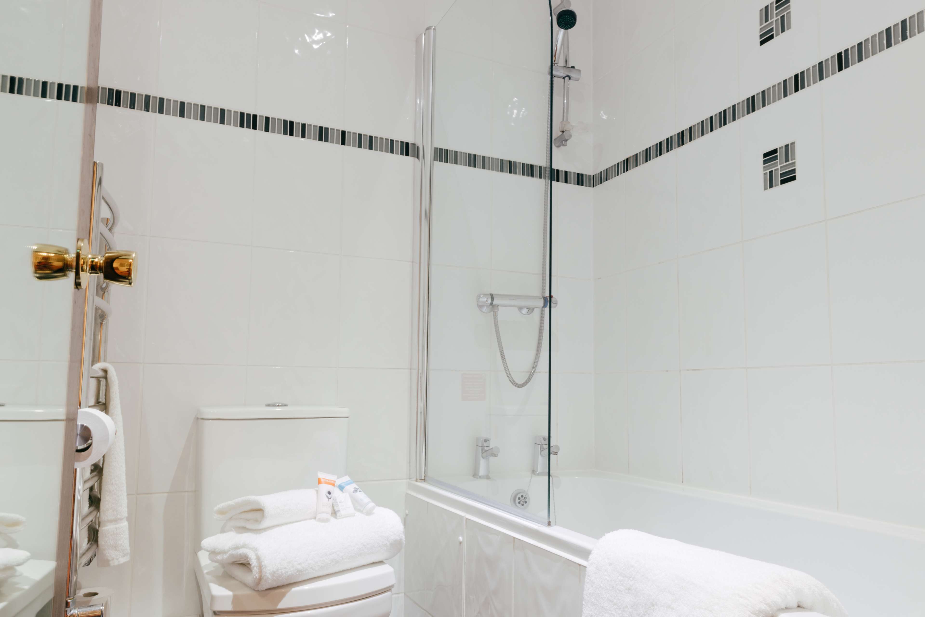 A modern bathroom with a glass-enclosed shower, a toilet, and a bathtub.