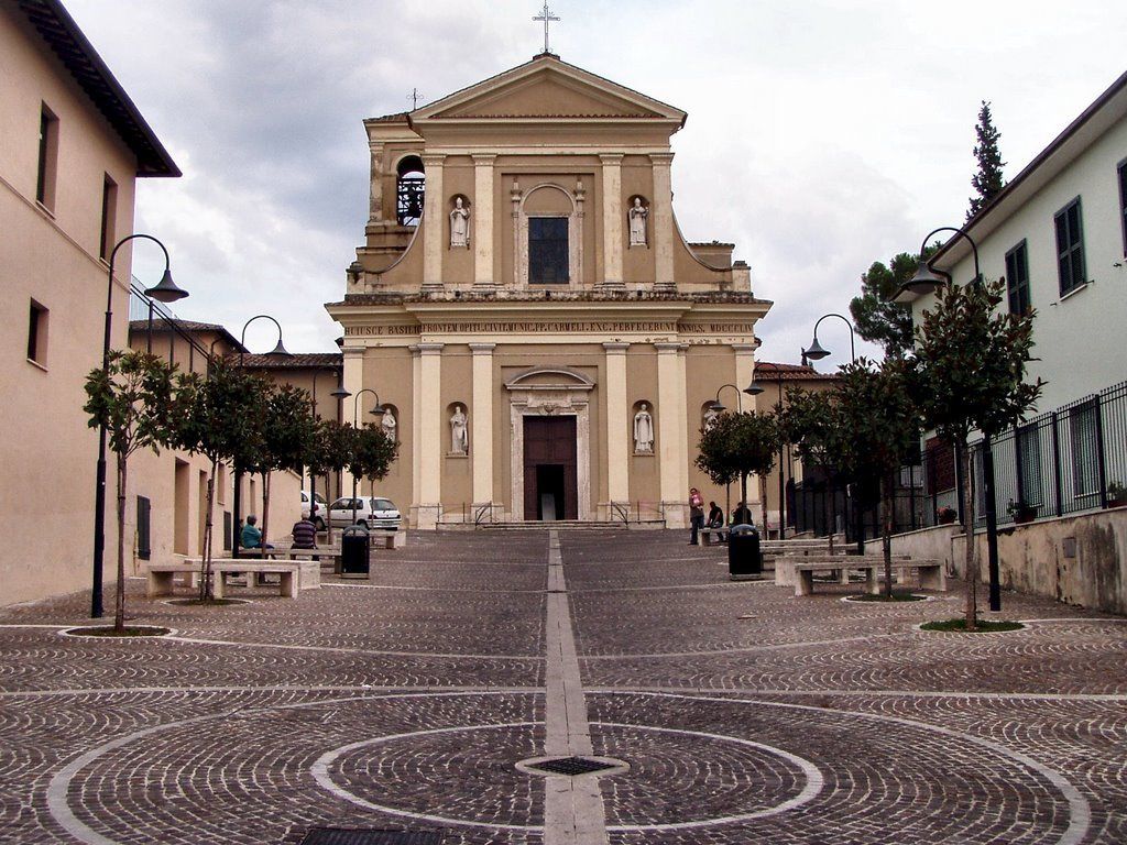 A church with a central dome and a bell tower, surrounded by a cobblestone square with benches and trees.