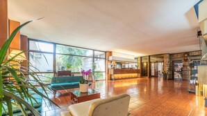 A spacious lobby with a green sofa, a beige armchair, and a reception desk. - Garden Hotel (Terni)