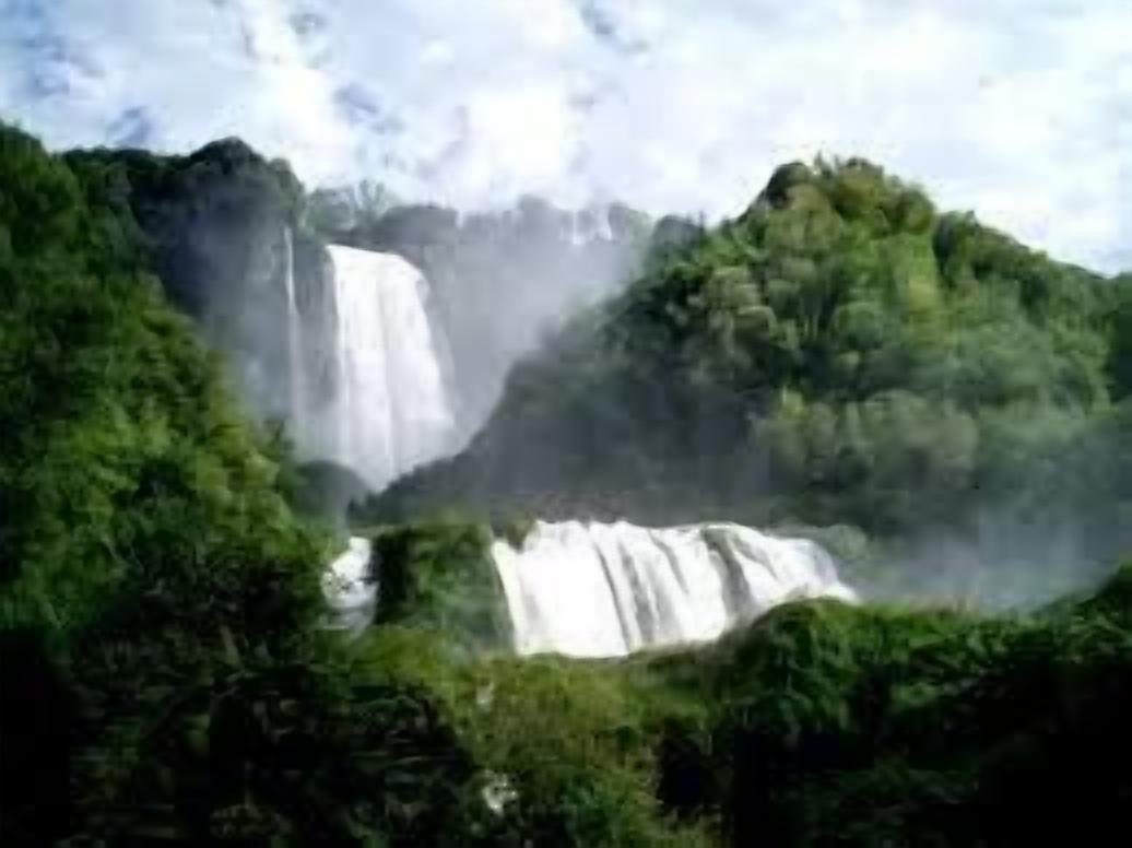 Ein Wasserfall, umgeben von üppiger Vegetation.