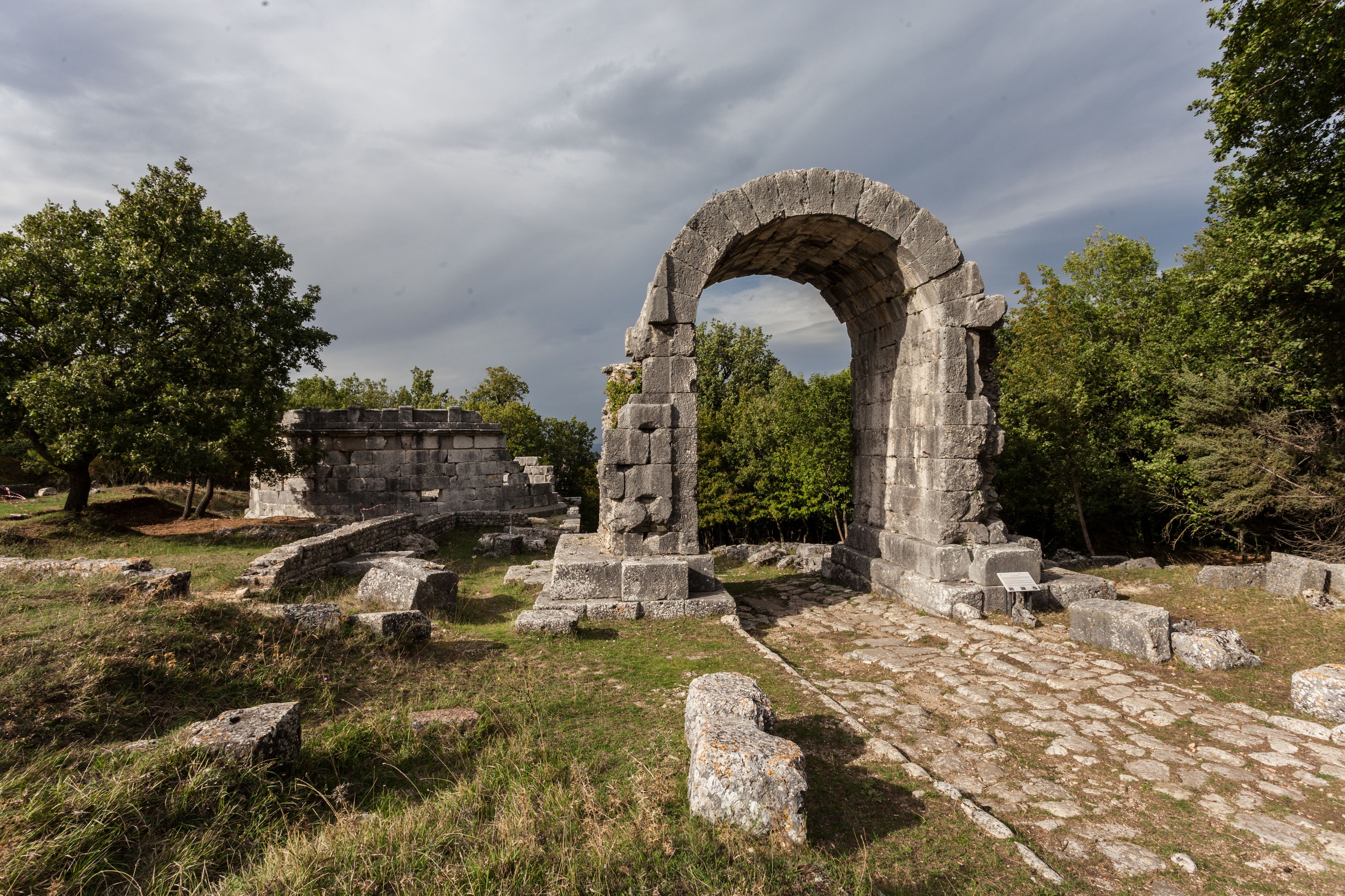 Ruinas antiguas con estructuras de piedra y un arcoado.