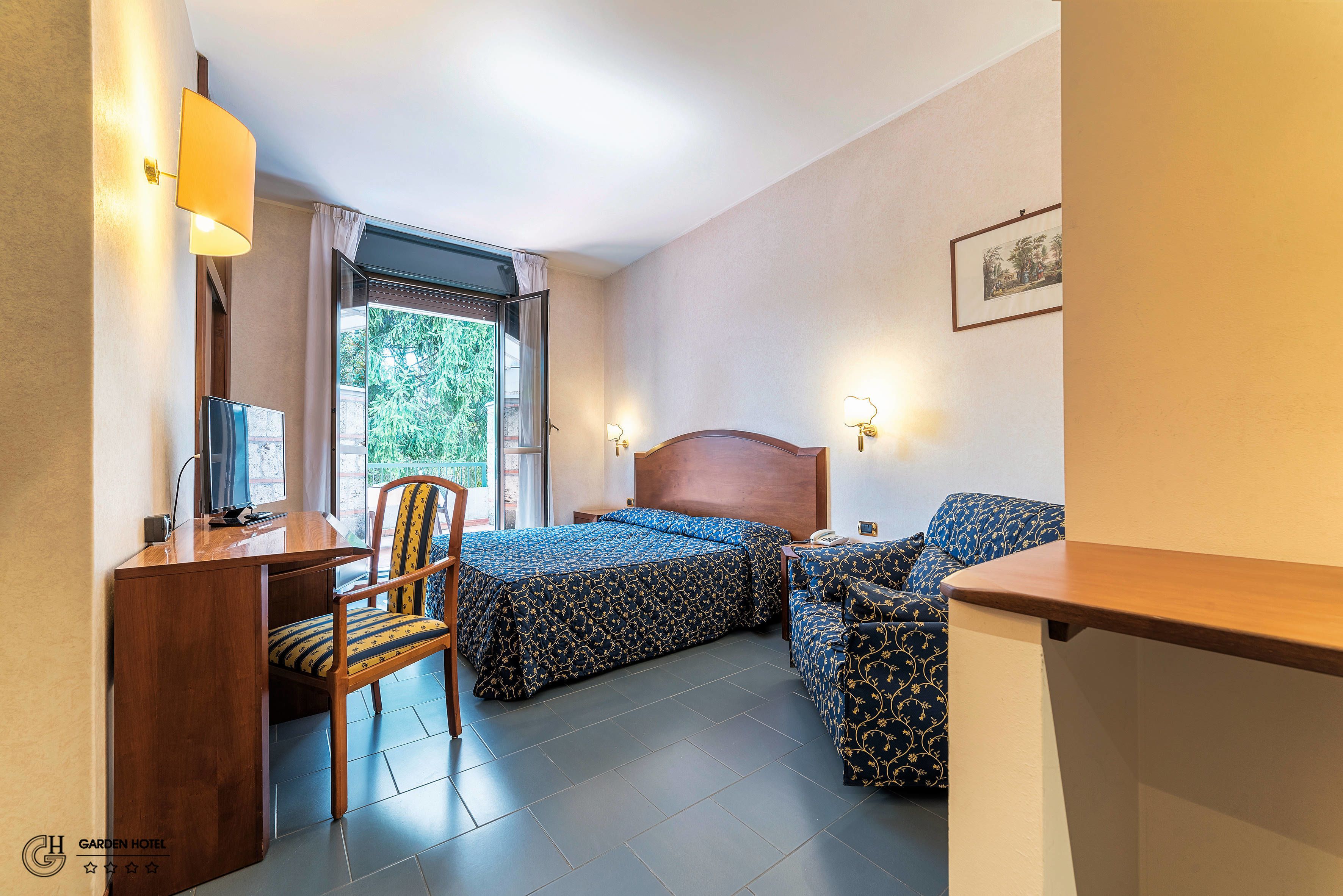 Una habitación de hotel con cama, escritorio, silla y sofá.