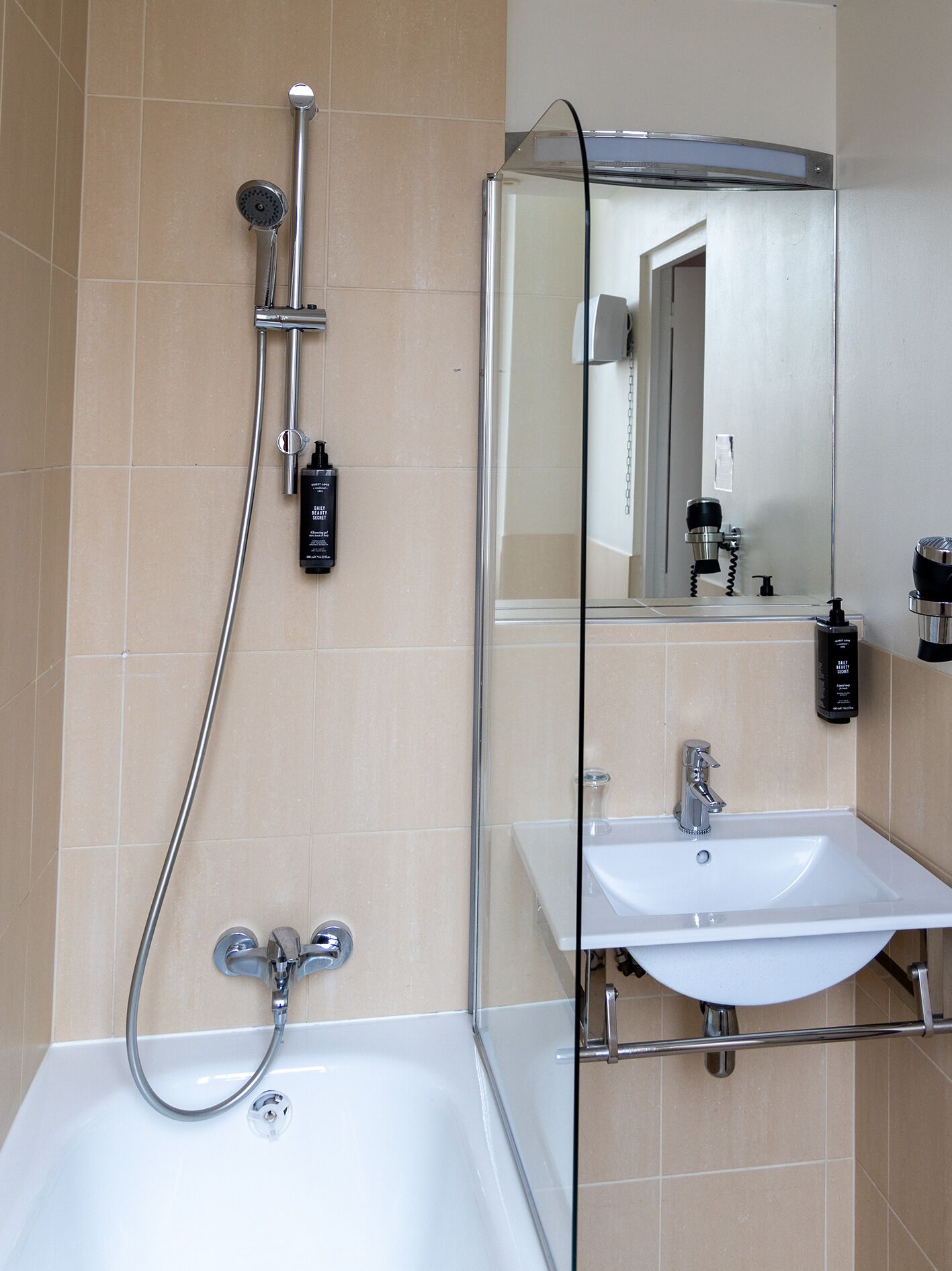 Un bagno moderno con una vasca, una doccia dotata di soffione manuale, un lavandino e uno specchio.