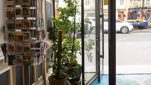A glass door entrance with a display of travel brochures and potted plants. - Hotel Le Clocher de Rodez (Toulouse)