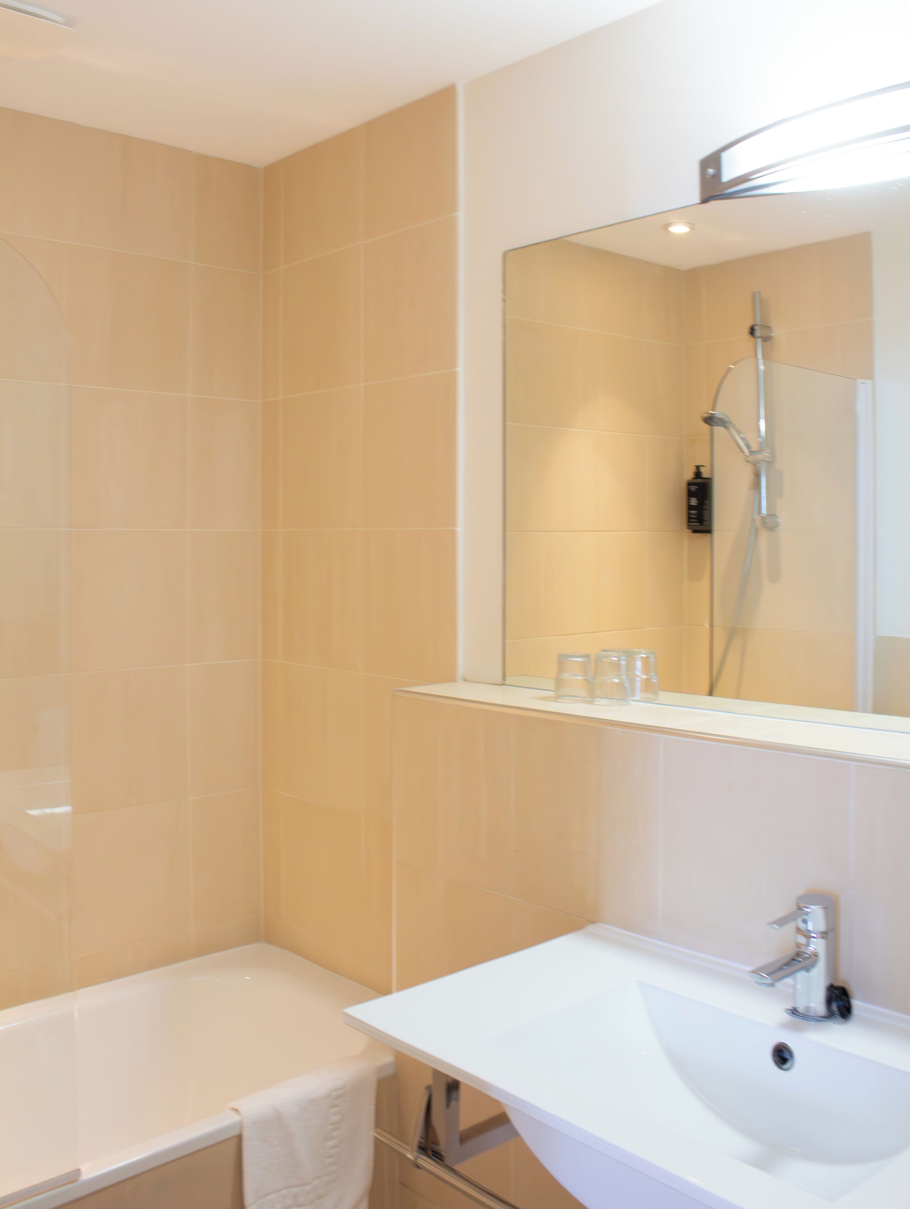 A bathroom with a bathtub, a sink, and a mirror.