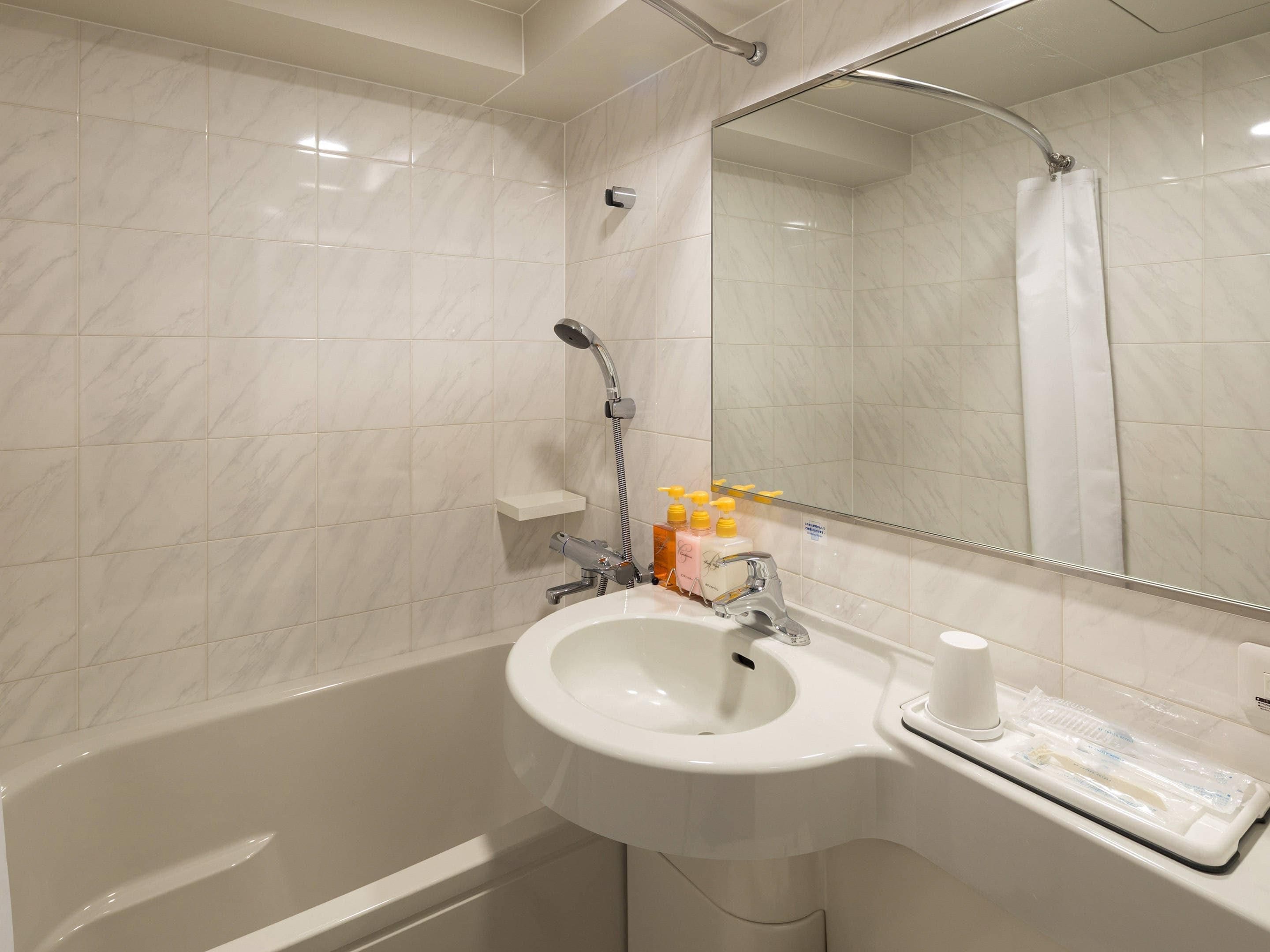 Une salle de bain moderne avec un lavabo en marbre blanc, une douchette à main et un miroir au-dessus du lavabo.