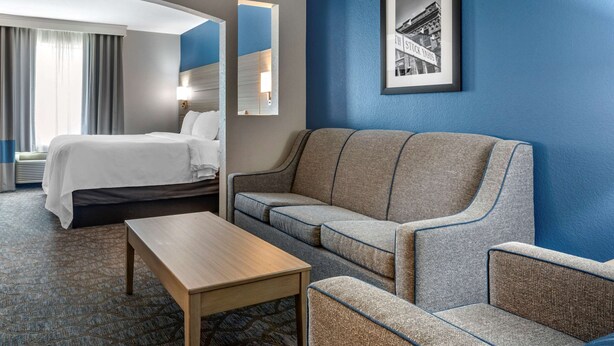 Une chambre d’hôtel avec un lit, un canapé, une table basse et un tableau encadré au mur.