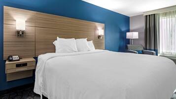 Een hotelkamer met een groot bed, nachtkastjes, een lamp en een stoel.