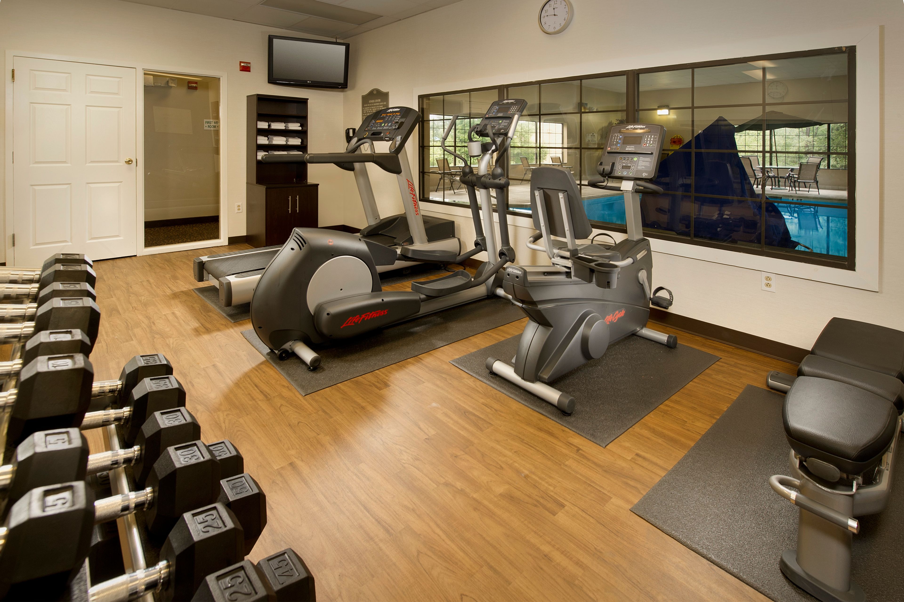Un gimnasio con cintas de correr, elípticas y mancuernas.