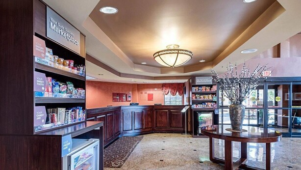A hotel lobby with a kitchenette area, a reception desk, and a decorative vase. - Comfort Suites Dulles Airport (Chantilly)