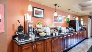 A hotel breakfast bar with a waffle maker, fruit bowls, and coffee machines. - Comfort Suites Dulles Airport (Chantilly)