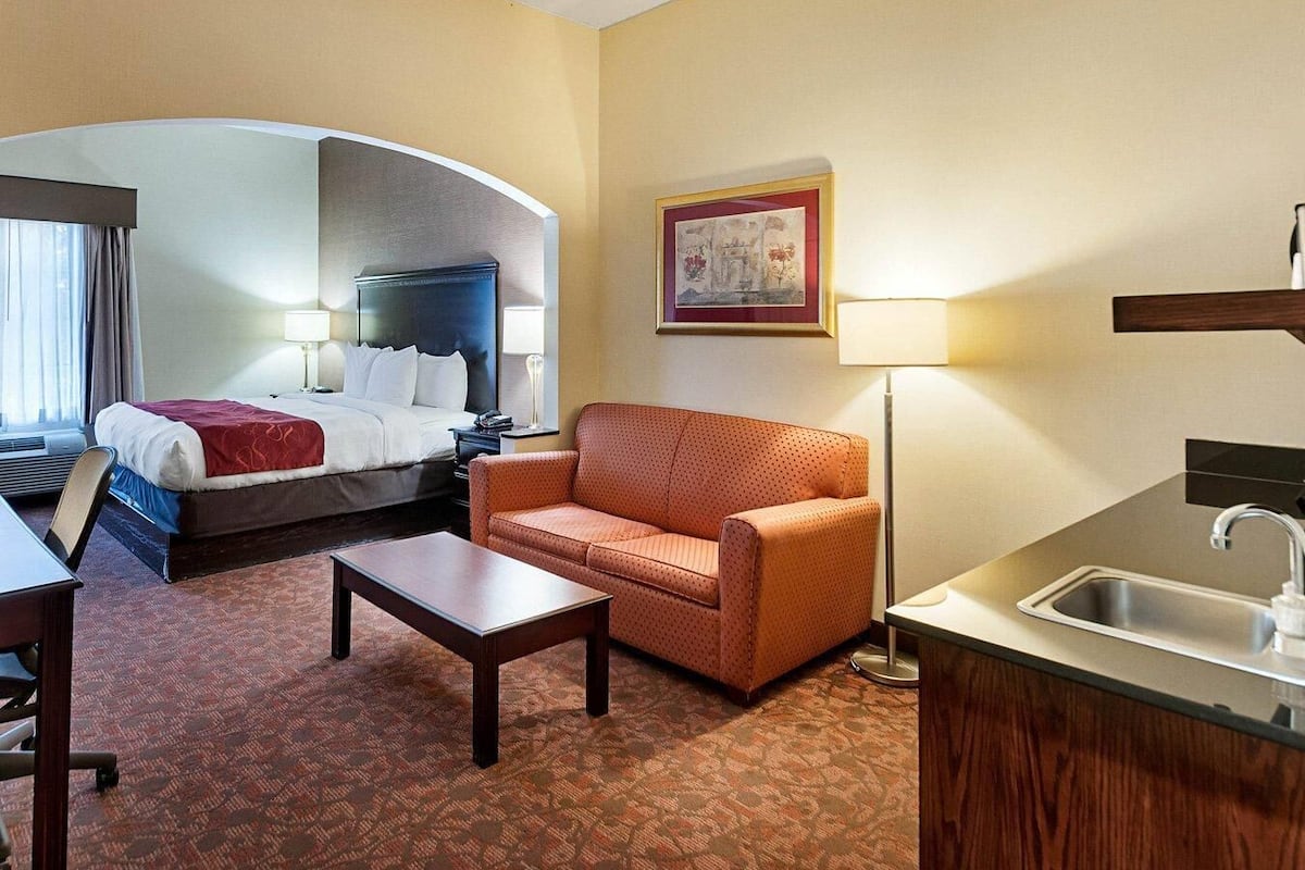 Ein Hotelzimmer mit Bett, Sofa, Couchtisch, Schreibtisch und einer Küchenzeile.