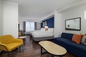 Una habitación de hotel con cama, sofá, escritorio y silla.