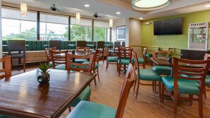 A restaurant with wooden tables and chairs, a television, and a popcorn machine.
