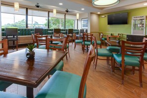 A restaurant with wooden tables and chairs, a television, and a popcorn machine. - Drury Inn & Suites Nashville Airport (Nashville)