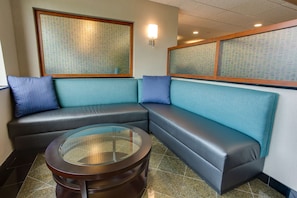 A modern waiting area with a curved sofa, a glass-top coffee table, and patterned privacy screens. - Drury Inn & Suites Nashville Airport (Nashville)