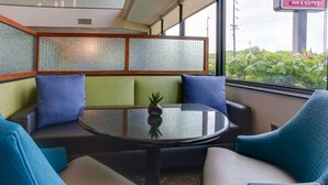 Un área de estar con una mesa redonda, sillas acolchadas y un florero decorativo.
