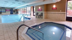 An indoor swimming pool with a no diving sign, chairs, and a lifeguard chair.