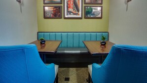 A restaurant interior with a booth seating arrangement, a green wall, and framed pictures above the booth.