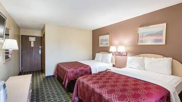 Une chambre d’hôtel avec deux lits, un bureau, une chaise, une lampe et une porte.