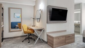Une chambre d’hôtel équipée d’un bureau, d’une chaise, d’une télévision et d’un miroir.