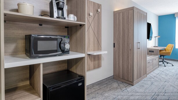 Une cuisine moderne équipée d’un four à micro-ondes, d’une machine à café et de placards de rangement.