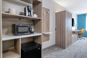 Una cocina moderna con microondas, cafetera y armarios de almacenamiento.