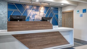 Un comptoir d’accueil au design moderne, avec une palette de couleurs bleues et grises et des motifs géométriques sur le mur.