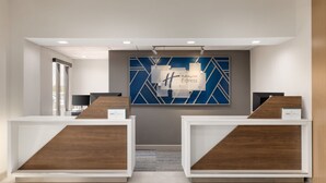 A reception area with two reception desks, a blue wall with geometric patterns, and a sign reading "Holiday Inn Express". - Holiday Inn Express & Suites Opelousas by IHG (Opelousas)
