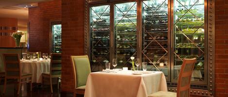A restaurant with brick walls, a glass display case with food items, and a table set for two.