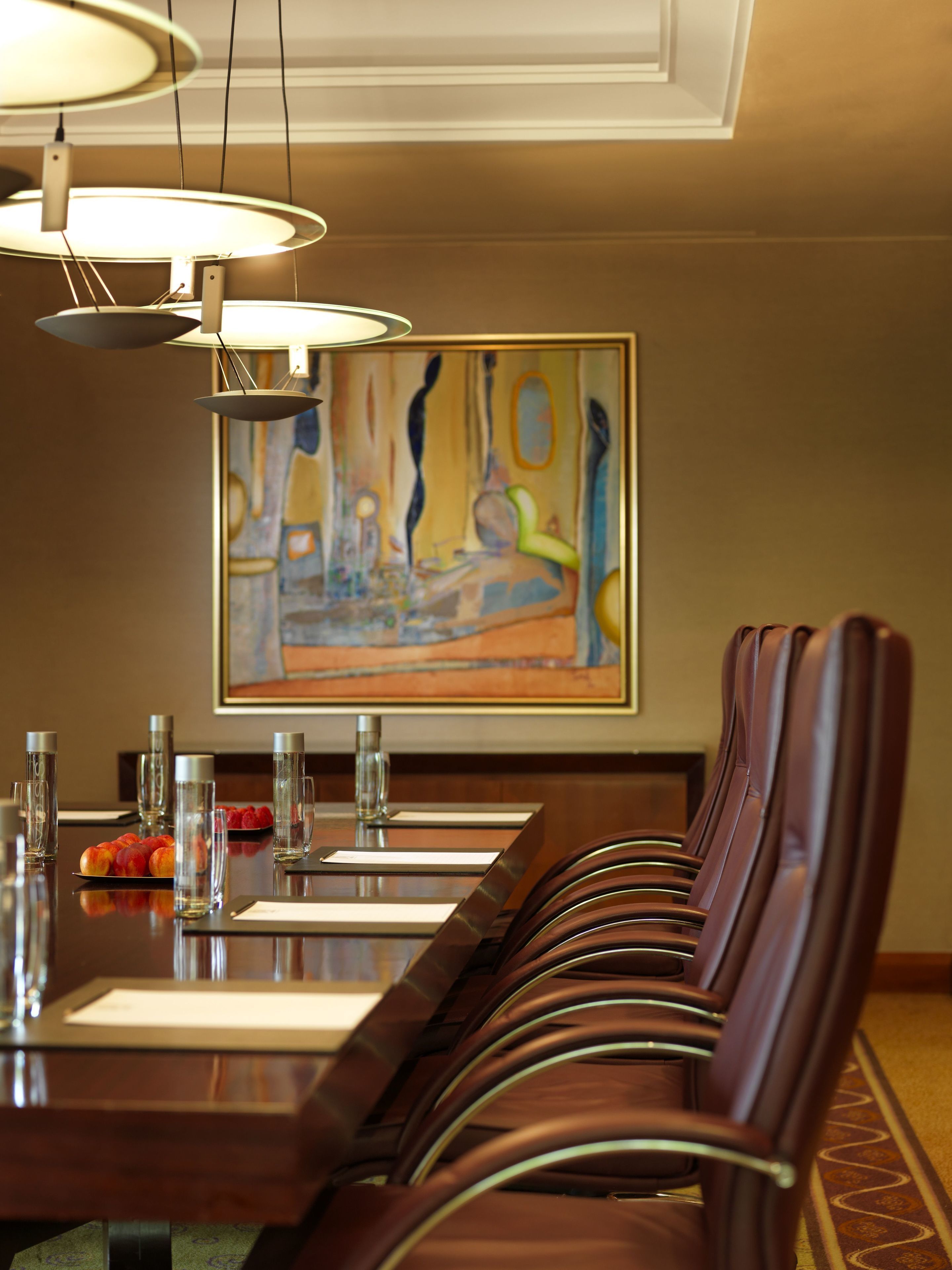 Un comedor con una larga mesa de madera, varias sillas y un cuadro en la pared.