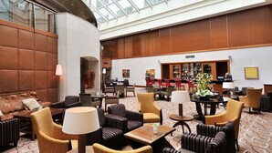 Un vestíbulo amplio con techo alto y un atrio de cristal, que cuenta con cómodas zonas de estar y una zona de bar/lounge.