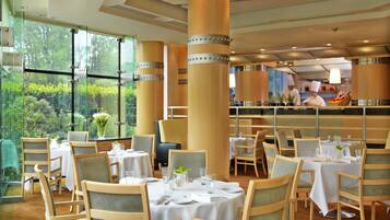 A restaurant with tables set for dining, large windows, and a view of the outdoors.