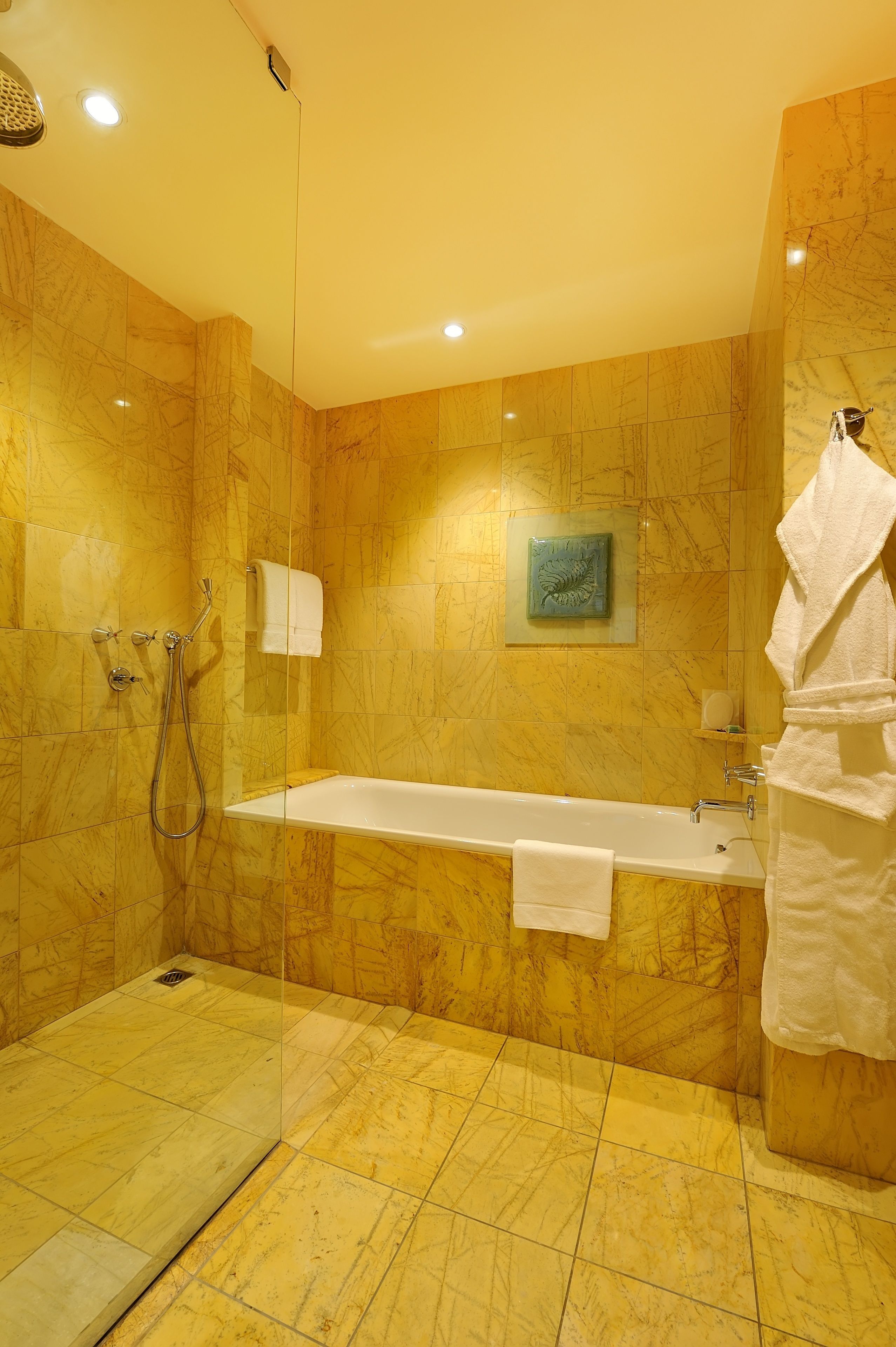 Un baño con bañera, ducha y zona de ducha con mampara de vidrio.