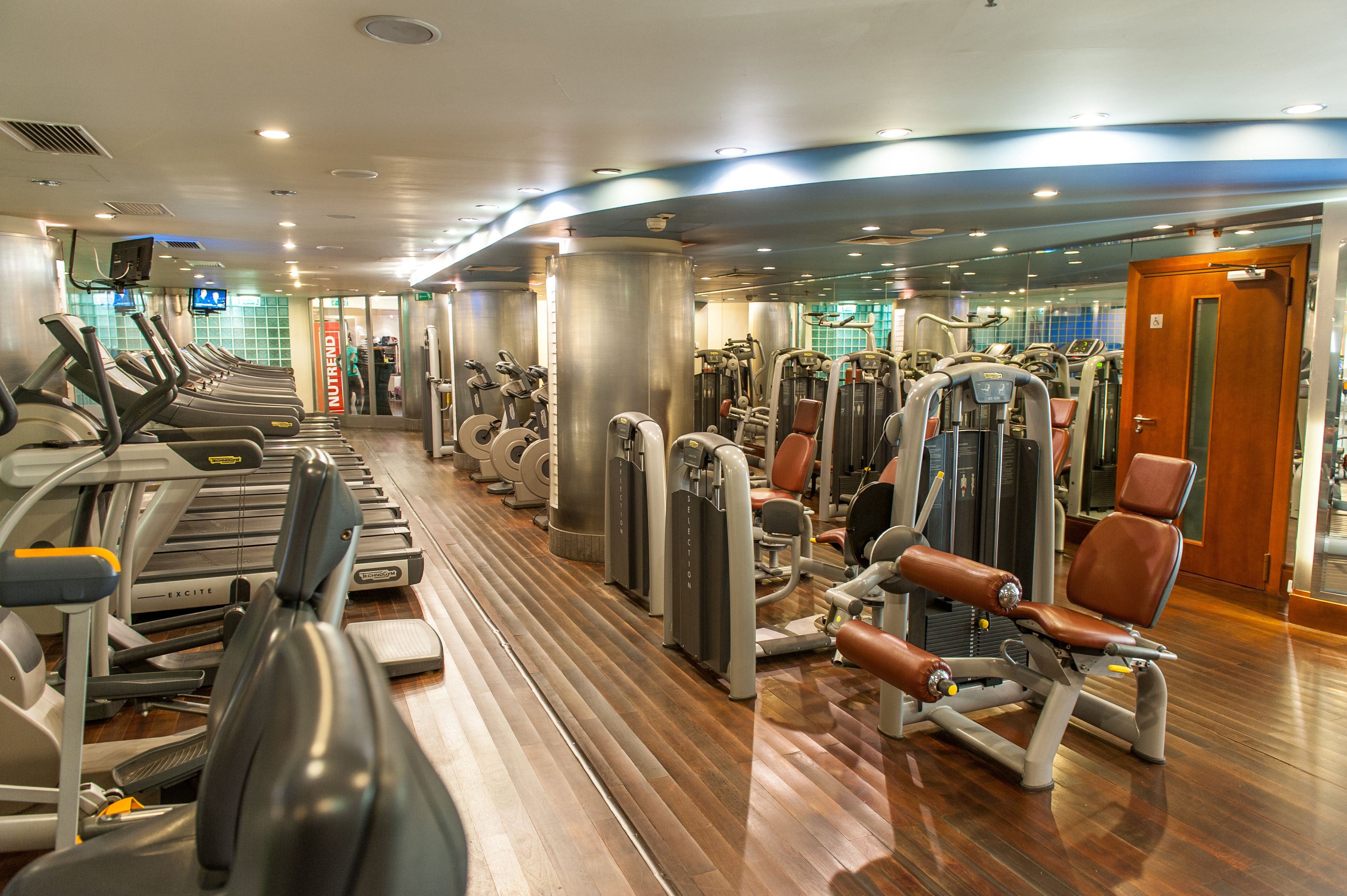 Een sportschool met loopbanden, krachtapparaten en fitnessapparatuur.