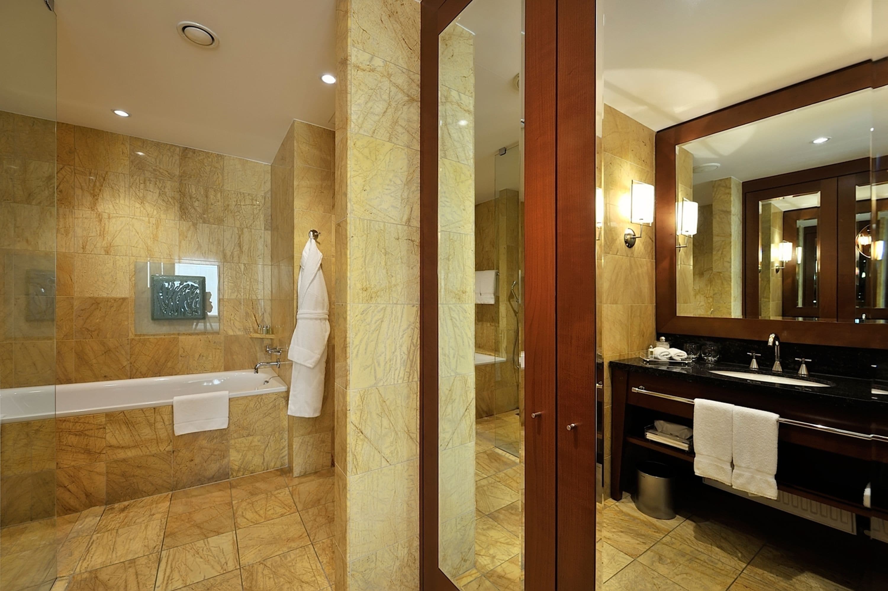 Un baño moderno con una bañera, un espejo grande y un tocador con lavamanos.