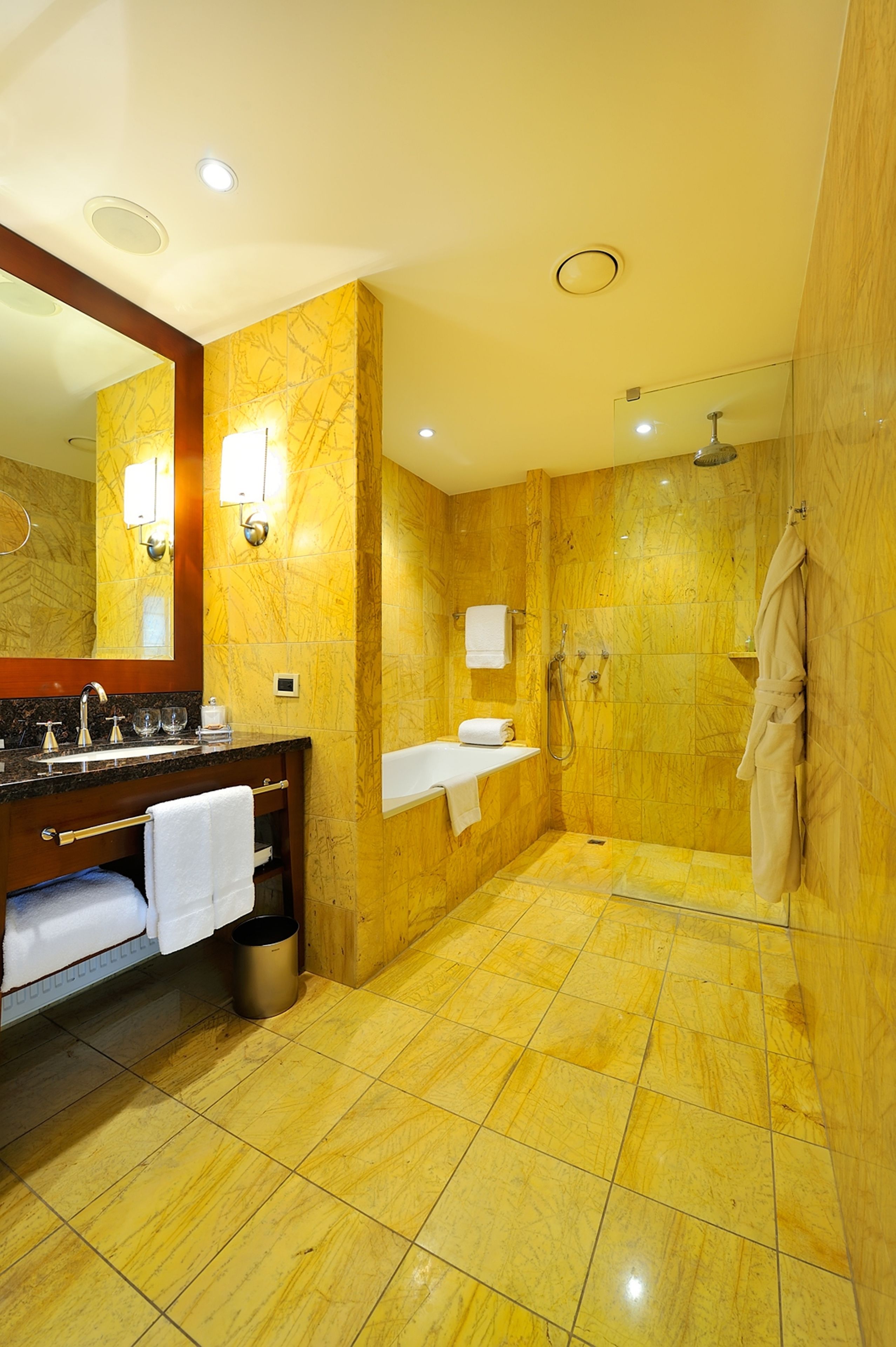 A bathroom with a marble floor, a sink with a towel, a mirror, and a shower area.