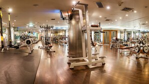 Un gimnasio moderno con diferentes máquinas de ejercicio, suelo de madera y pared espejada.