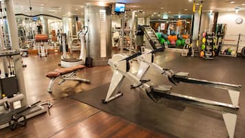 A gym with various exercise equipment, including a rowing machine, weight bench, and free weights.