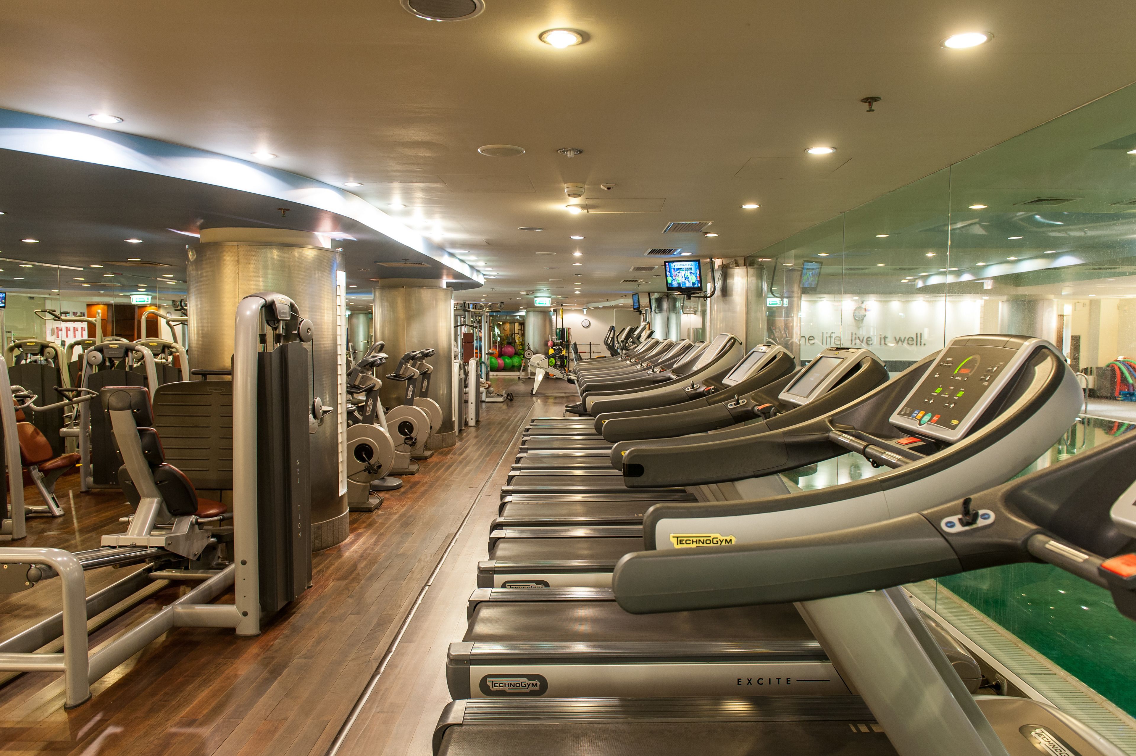 Un gimnasio con cintas de correr, máquinas de pesas y pelotas de ejercicio.