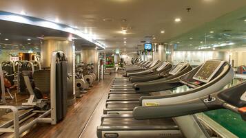Un gimnasio con cintas de correr, máquinas de pesas y pelotas de ejercicio.