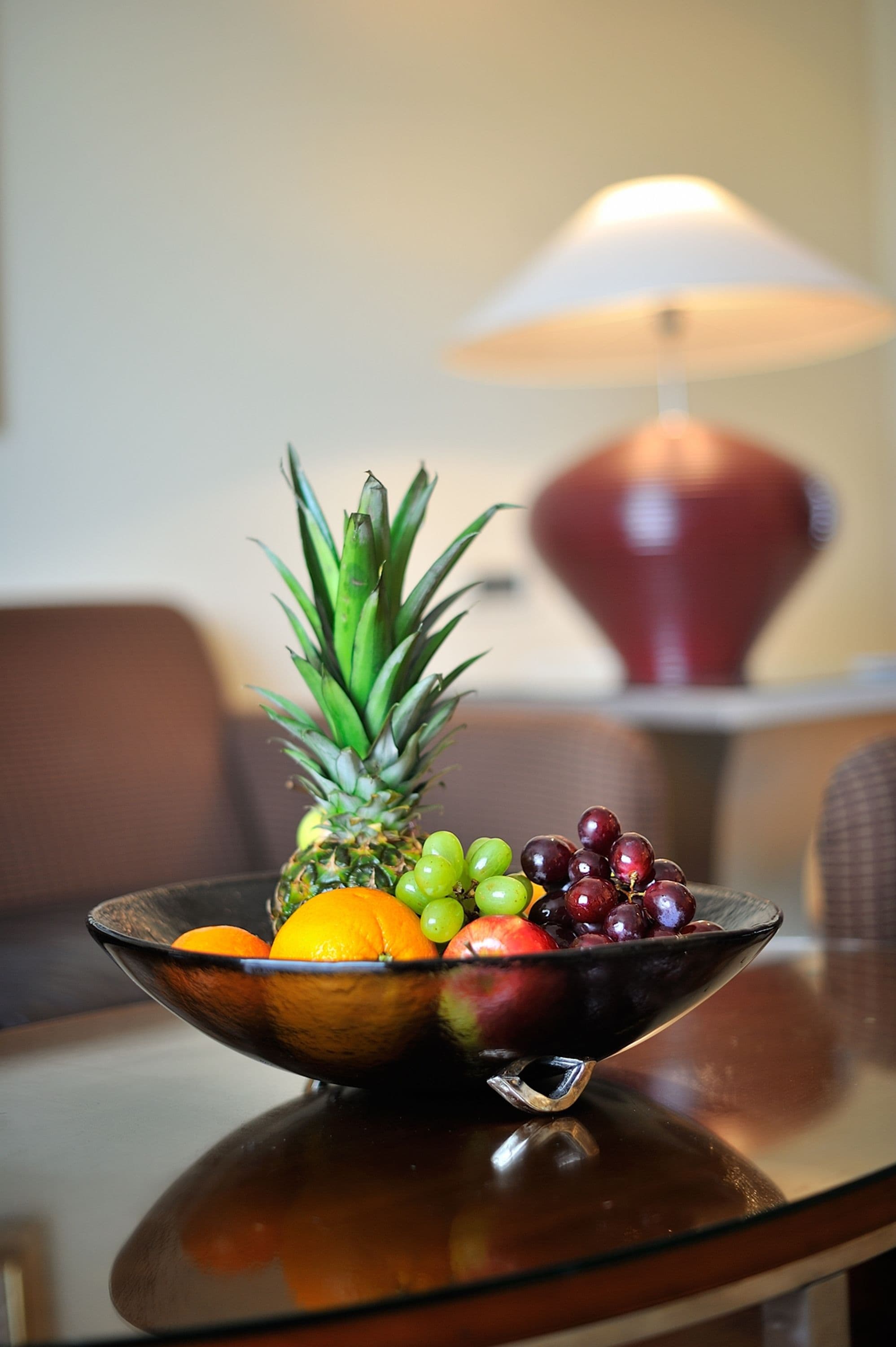 Un frutero sobre una mesa, con una lámpara al fondo.