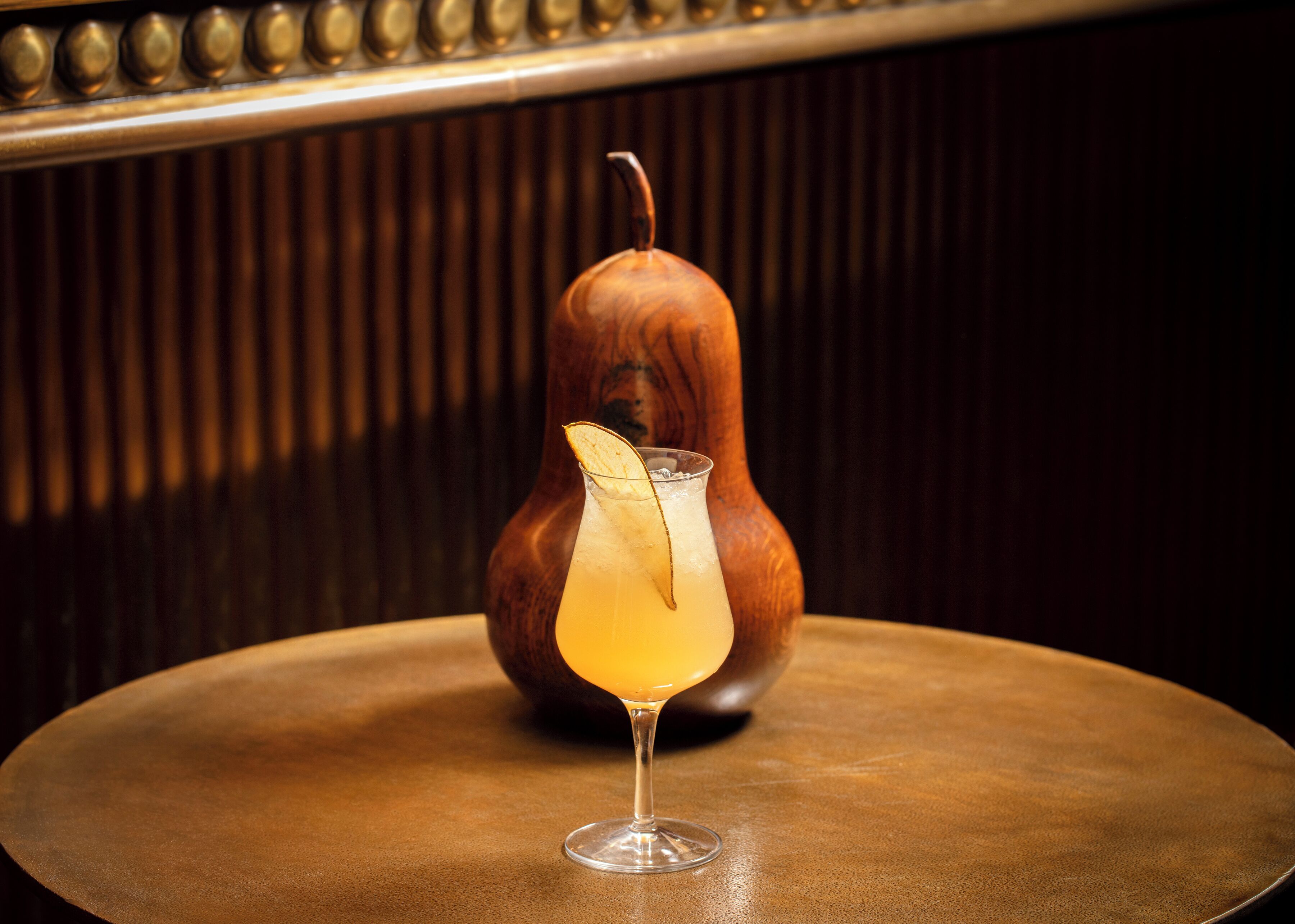 A cocktail glass with a lemon slice garnish on a round table.