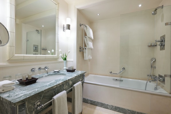 Un bany modern amb un lavabo de marbre, un mirall gran, una dutxa envidriada i una banyera.