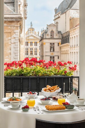 A breakfast table with a variety of foods and a flower box with red flowers.